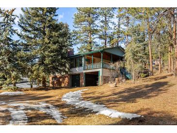 Ranch style home nestled in a wooded area with a large porch at 5274 S Hatch Dr, Evergreen, CO 80439