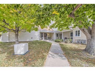 Tan siding condo building with walkway, landscaping, and a tree with fall leaves at 2604 S Xanadu Way # B, Aurora, CO 80014