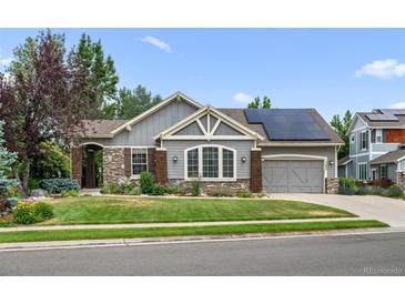 Ranch-style home with gray siding, stone accents, and solar panels at 17085 W 62Nd Cir, Arvada, CO 80403