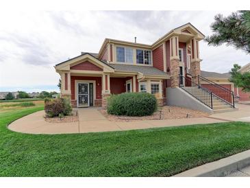 Two-story home with red exterior, landscaping, and walkway at 13722 Legend Way # 101, Broomfield, CO 80023