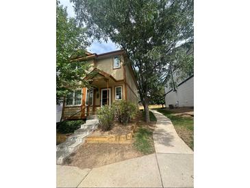 Two-story tan home with a front porch, steps, and landscaping at 1514 S Buckley Way, Aurora, CO 80017
