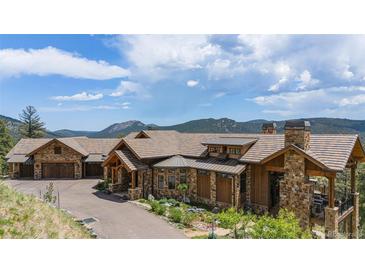 Mountain home with stone exterior and large driveway at 456 Crystal Ridge Rd, Evergreen, CO 80439