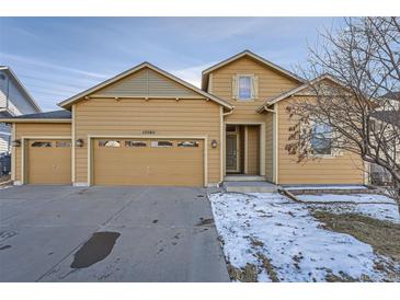 Tan two-story house with a three-car garage and landscaped yard at 15505 Carob Cir, Parker, CO 80134