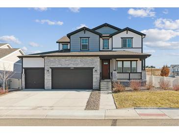 Two-story home with gray and white siding, stone accents, and a two-car garage at 5694 Pinto Valley St, Parker, CO 80134