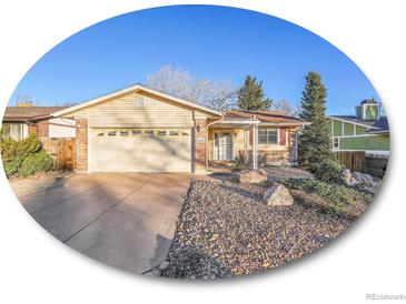 House exterior featuring a two-car garage and landscaped front yard at 2450 S Deframe St, Lakewood, CO 80228