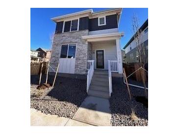 Two-story home with stone and gray siding, front porch, and landscaping at 21132 E 63Rd Dr, Aurora, CO 80019