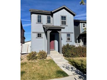 Two-story house with gray siding, red door, and landscaped front yard at 19085 E 66Th Ave, Denver, CO 80249