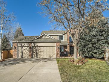 Two-story brick home with three-car garage and landscaped front yard at 6579 Poppy St, Arvada, CO 80007