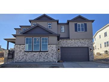 Two-story house with gray siding, dark gray garage door, and stone accents at 1658 Fox Trotter Pt, Castle Rock, CO 80104