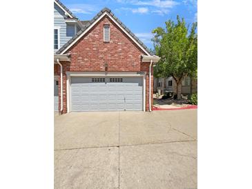 Attached garage with gray door, belonging to a brick home at 22975 E Ontario Dr # 101, Aurora, CO 80016