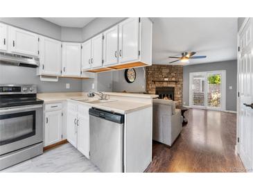 Kitchen with white cabinets, stone accent wall, and stainless steel appliances at 8140 S Fillmore Cir, Centennial, CO 80122