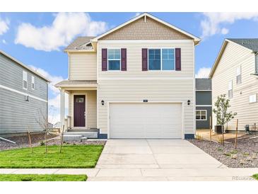 Two-story house with beige siding, a two-car garage, and a well-manicured lawn at 849 Crest St, Lochbuie, CO 80603