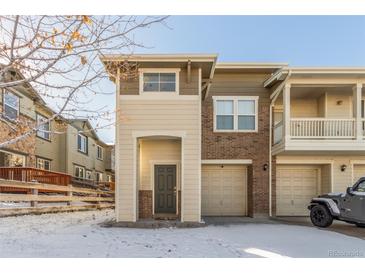 Tan and brown two-story townhome with a two-car garage and snowy front yard at 13043 Grant Cir # C, Thornton, CO 80241