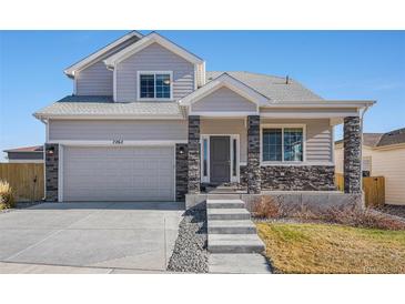 Two-story house with gray siding, stone accents, and a two-car garage at 7262 Xenophon Ct, Arvada, CO 80005