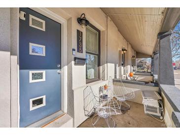 Front porch of a charming home with gray door and white chairs at 1735 E 35Th Ave, Denver, CO 80205