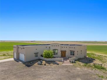 Single-story stucco home with attached garage, situated on a large lot with expansive views at 6001 S County Road 161, Strasburg, CO 80136