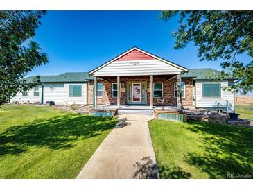 Ranch style home with brick and siding, covered porch, and landscaped yard at 6751 S County Road 129, Bennett, CO 80102