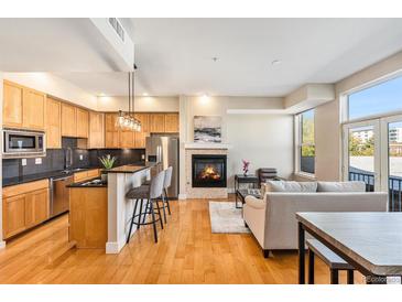 Open concept kitchen and living room with hardwood floors and fireplace at 1738 N Franklin St # 3C, Denver, CO 80218