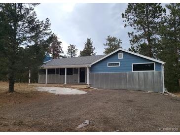 Ranch style home with blue siding, porch, and gravel driveway at 11967 W Ranch Elsie Rd, Golden, CO 80403