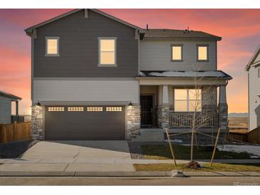 Two-story house with beige and brown siding, a two-car garage, and a landscaped yard at 9129 Pitkin St, Commerce City, CO 80022