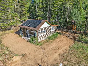 Aerial view of a rustic log cabin with solar panels at 9719 Beaver Pond, Conifer, CO 80433