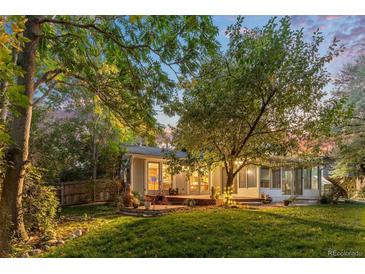 Spacious backyard with a deck and mature trees, at dusk at 9641 Sierra Dr, Arvada, CO 80005