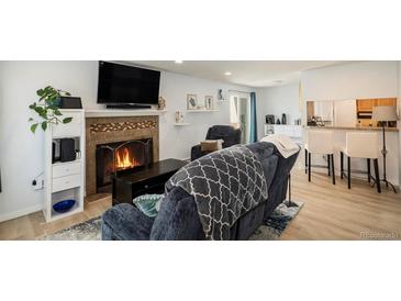 Cozy living room features a fireplace, comfortable seating, and hardwood floors at 13 Nome Way # A, Aurora, CO 80012
