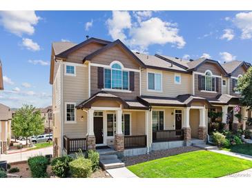 Tan three-story townhome with brown accents, front porch, and landscaping at 1423 Turnberry Pl, Castle Rock, CO 80104