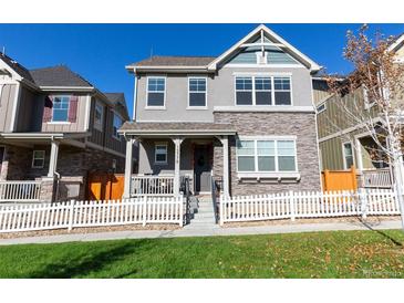 Two-story townhome with stone and siding exterior, front porch, and white picket fence at 13778 Umatilla Ln, Broomfield, CO 80023