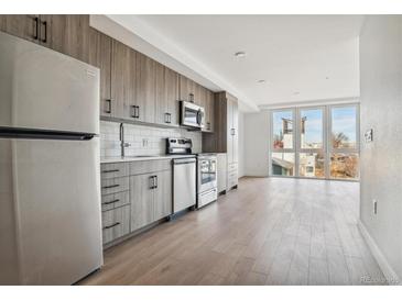 Modern kitchen with stainless steel appliances and wood cabinets at 3575 Chestnut Pl # 601, Denver, CO 80216