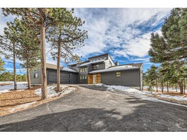 Modern two-story home with a gray exterior, wood accents, and a long driveway at 1298 Silverheels Dr, Larkspur, CO 80118