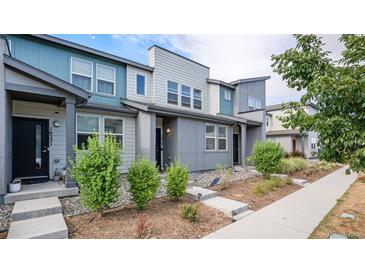 Modern townhome exterior with gray and teal siding, landscaping, and walkway at 16231 E Warner Pl, Denver, CO 80239