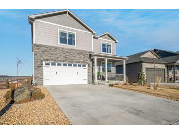 Two-story house with gray siding, stone accents, and a white garage door at 15946 Little Bluestem Rd, Monument, CO 80132