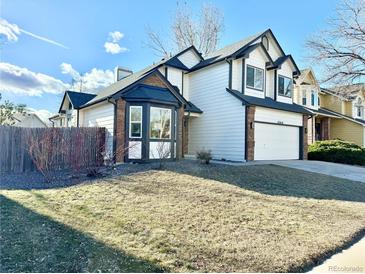 Two-story home with a brick and white exterior, landscaped lawn, and attached garage at 12414 W 85Th Ave, Arvada, CO 80005