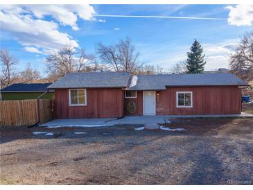 Red one-story home with a gravel driveway and fenced yard at 8182 3Rd Ave, Arvada, CO 80007