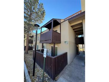 Exterior view of condo building showcasing a private balcony and fenced patio area at 9725 E Harvard Ave # 322, Denver, CO 80231