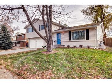 Ranch style home with landscaped yard, attached two-car garage, and a blue front door at 10100 W Grand Ave, Littleton, CO 80127