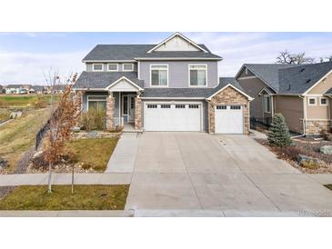 Two-story home with gray siding, stone accents, and a three-car garage at 5049 Liverpool St, Denver, CO 80249