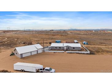 Aerial view of a house, detached garage, and additional storage buildings on a large lot at 11286 County Road 49, Hudson, CO 80642