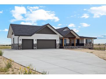 Two-story modern farmhouse with stone and white siding, two-car garage at 7340 Van Sickle St, Strasburg, CO 80136