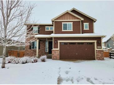 Two-story house with brown siding, three-car garage, and snow-covered lawn at 6242 N Genoa St, Aurora, CO 80019