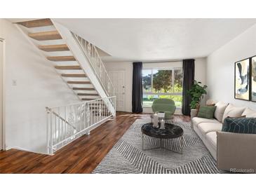 Living room with hardwood floors, staircase, and neutral decor at 1289 S Monaco Pkwy, Denver, CO 80224