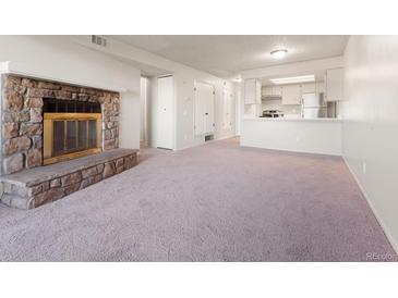 Cozy living room features a stone fireplace and sliding glass door leading to a balcony at 4274 S Salida Way # 3, Aurora, CO 80013