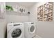 Laundry room with Whirlpool washer and dryer and stylish wall decor at 9916 Ceylon Ct, Commerce City, CO 80022