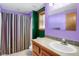 Bathroom with purple walls, striped shower curtain, and wood vanity at 3619 Estates Cir, Larkspur, CO 80118