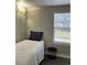 Small bedroom with twin bed, window, and grey wood-look floors at 4899 S Dudley St # 1E, Littleton, CO 80123