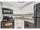 View of a galley kitchen with white cabinets and black appliances at 8701 Huron St # 1-210, Thornton, CO 80260