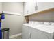 Bright laundry room with washer, dryer, and overhead cabinets at 6747 Raritan Dr, Denver, CO 80221