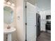 Small bathroom with pedestal sink, round mirror, and view into kitchen at 10291 E 62Nd Pl, Denver, CO 80238