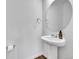 Simple bathroom with pedestal sink, round mirror, and dark wood flooring at 210 S Old Hammer Ct, Aurora, CO 80018